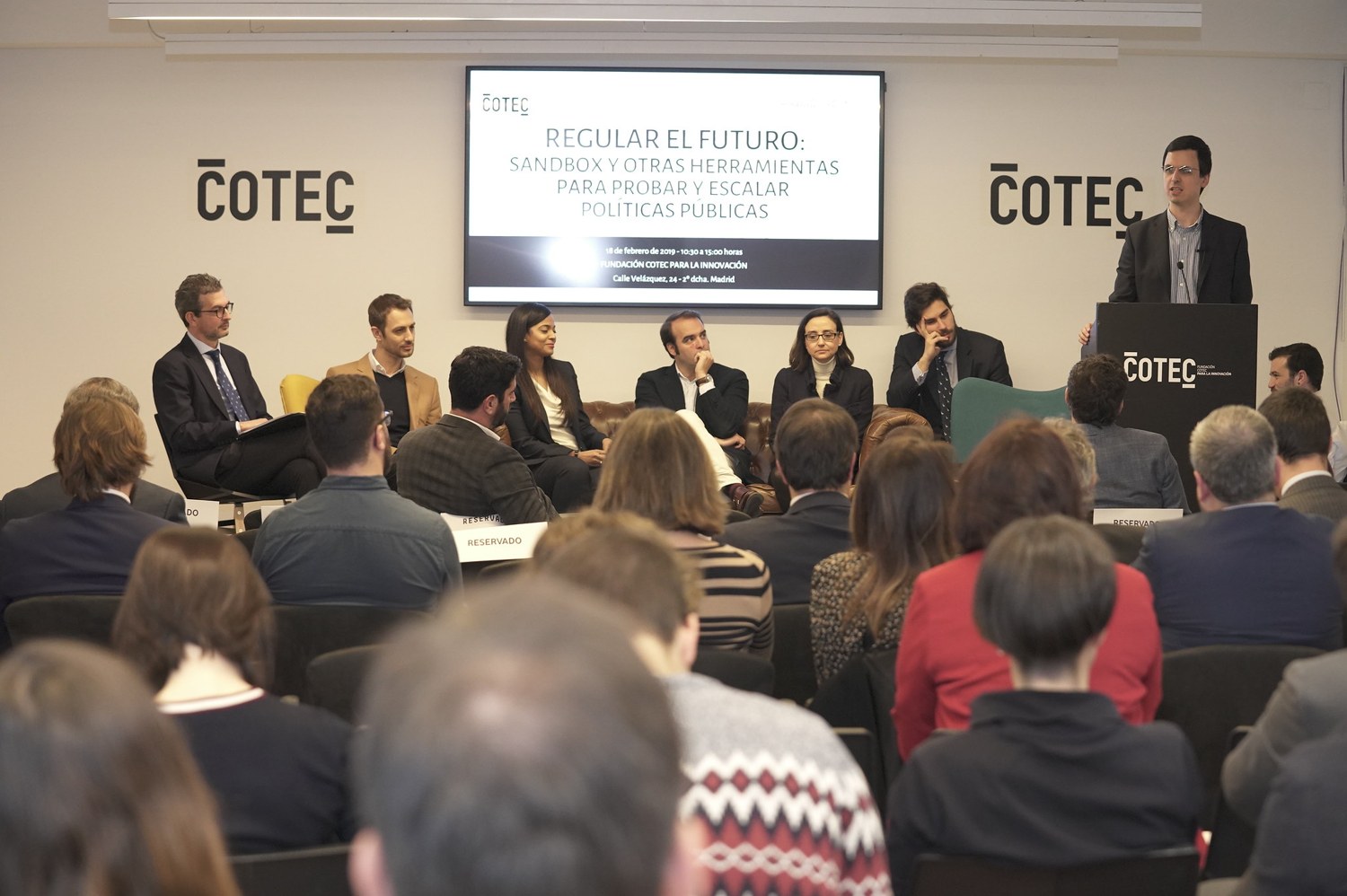 Aitor Fernández habla desde el atril de Cotec ante el público y los participantes de la jornada sobre sandbox.