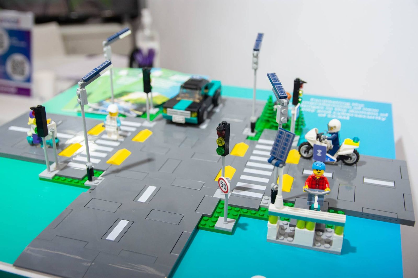 Maqueta de un cruce urbano con semáforos, un coche, un ciclista y una silla de ruedas